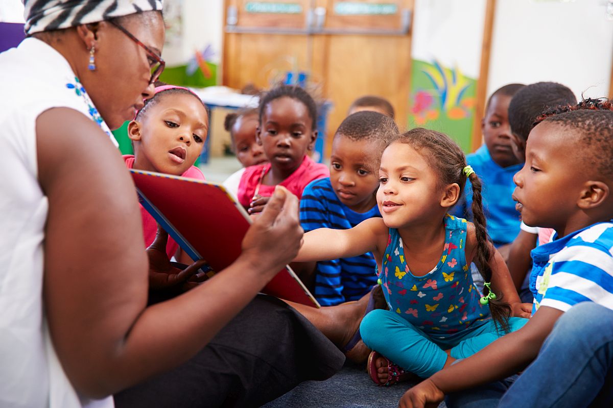 teacher reading a picture book to preschool students; national teacher awards concept