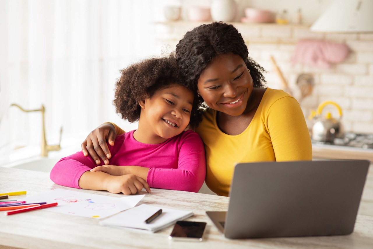 mother and daughter do schoolwork on laptop in kitchen; remotely engage young students concept