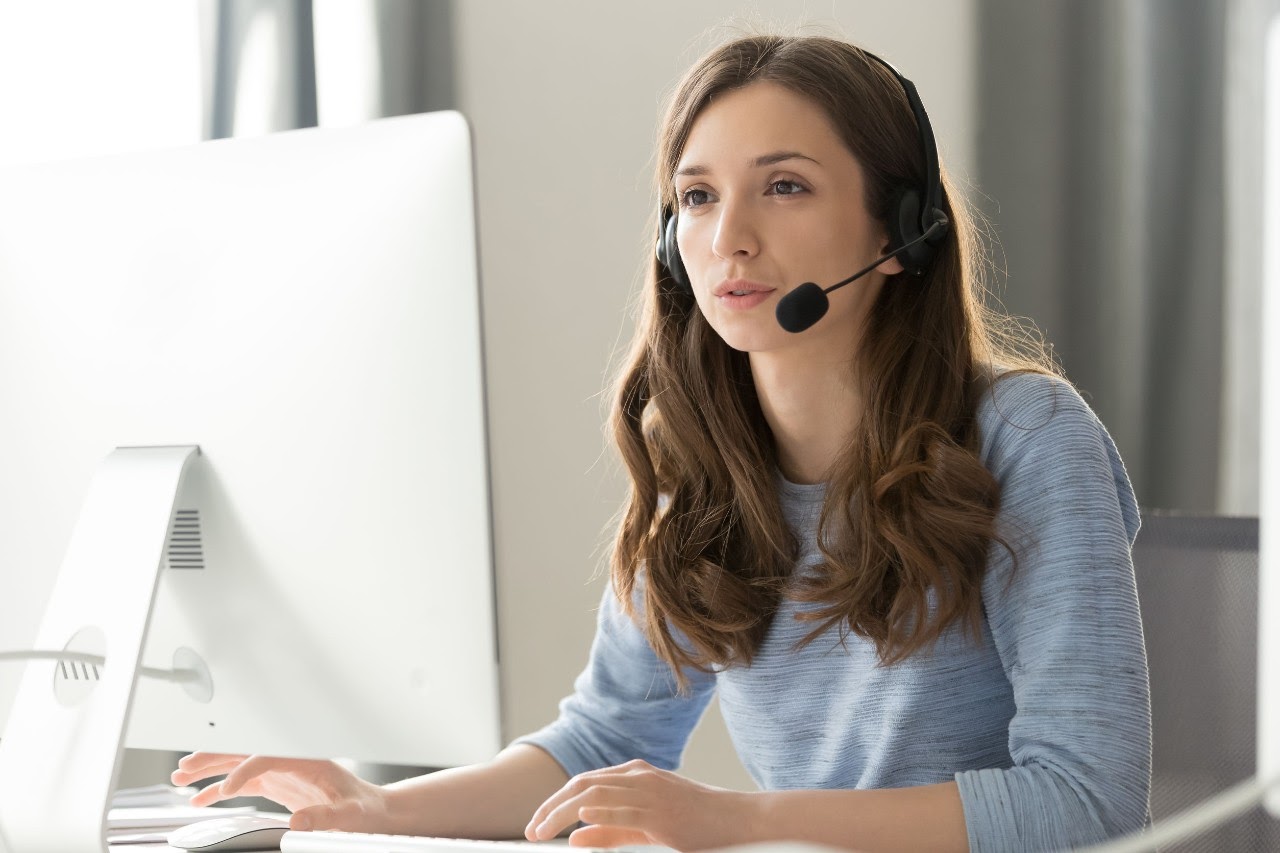 woman at computer wearing headset; teacher burnout concept