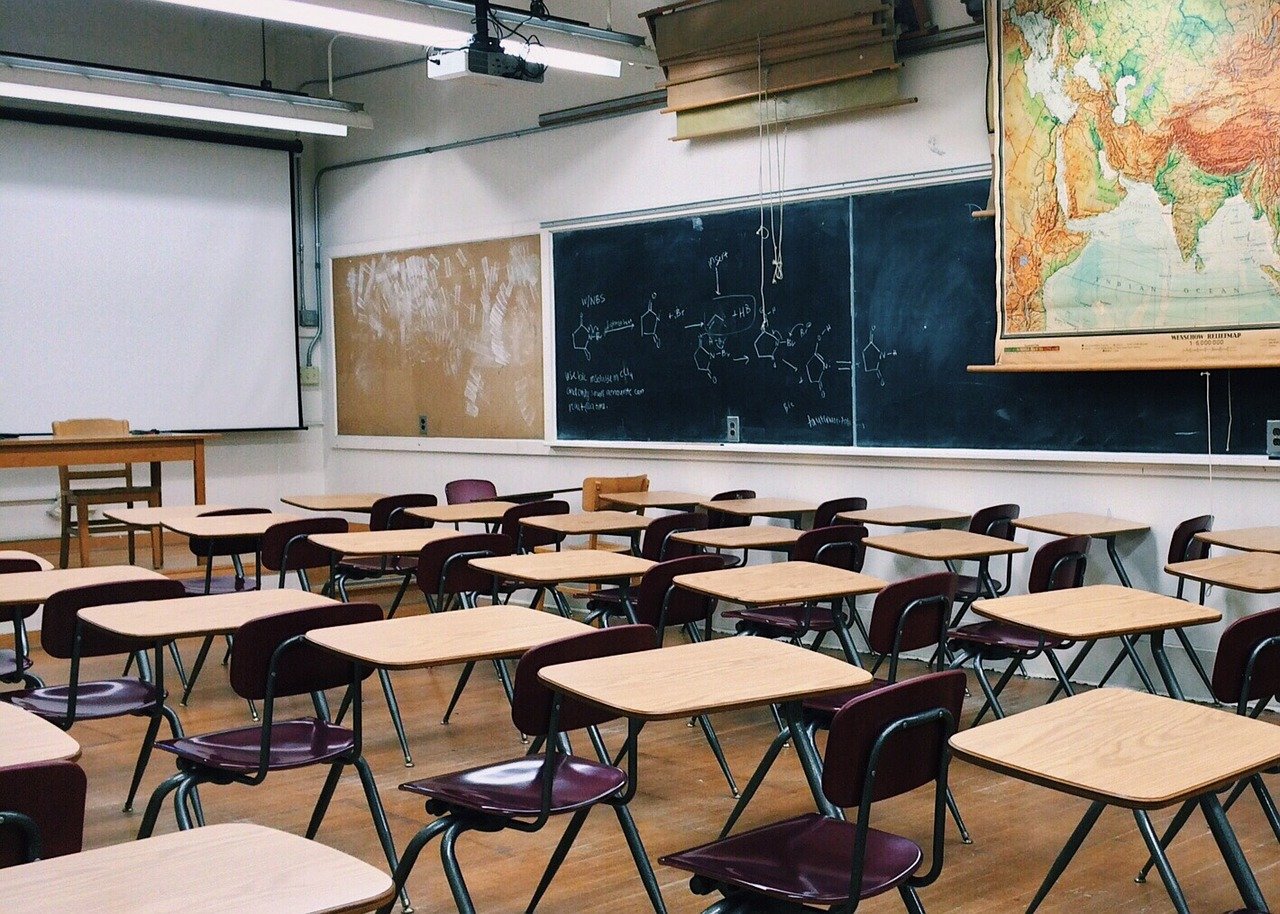 an empty classroom with rows of desks; fall 2021 return to classroom concept