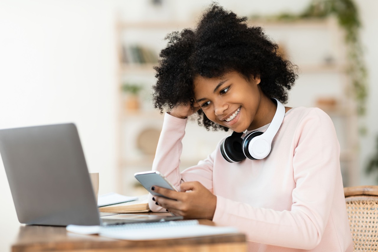 student in headphones smiling at laptop; make teaching history fun concept