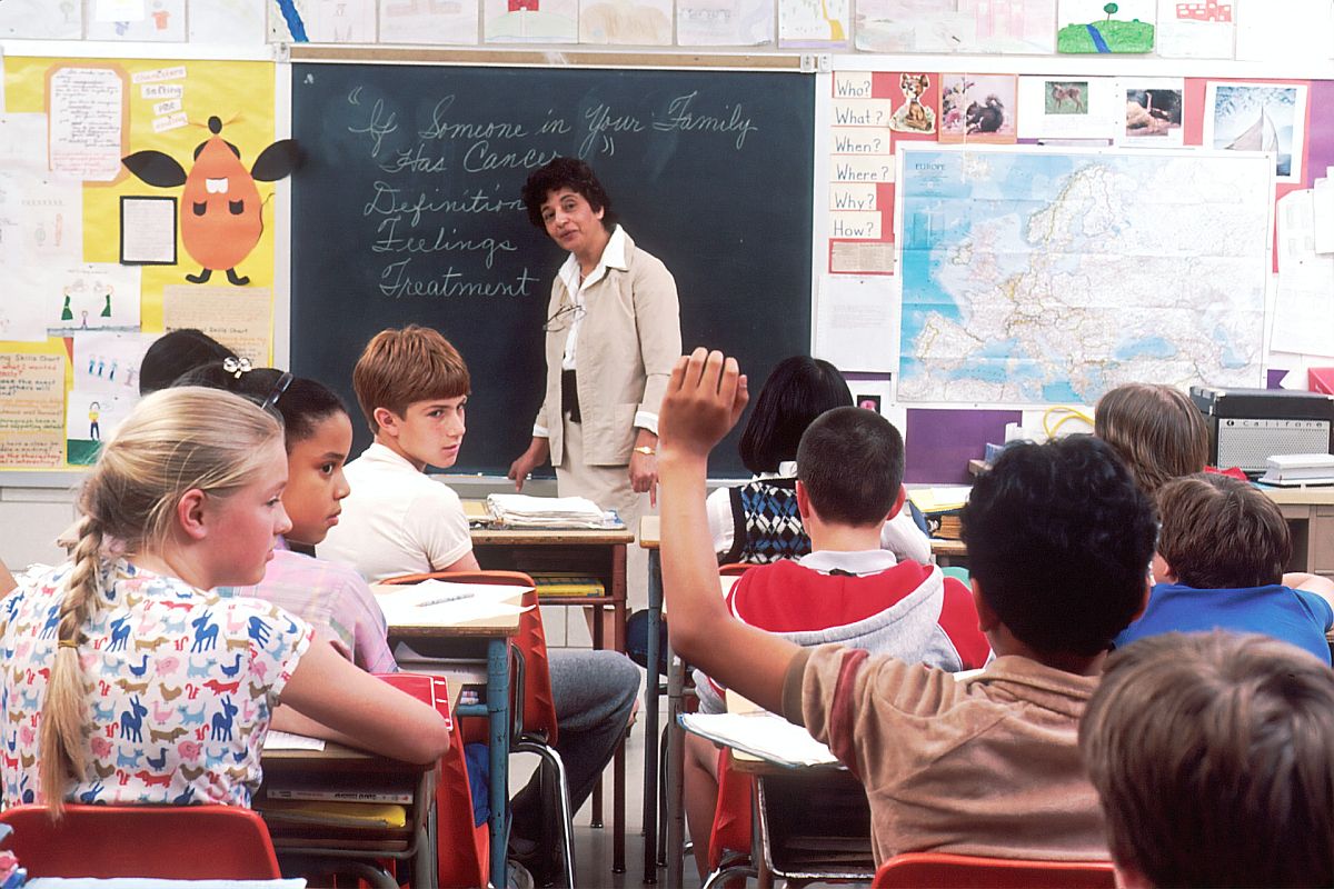 in a classroom students look frustratedly at a child with his hand raised; classroom behavior concept