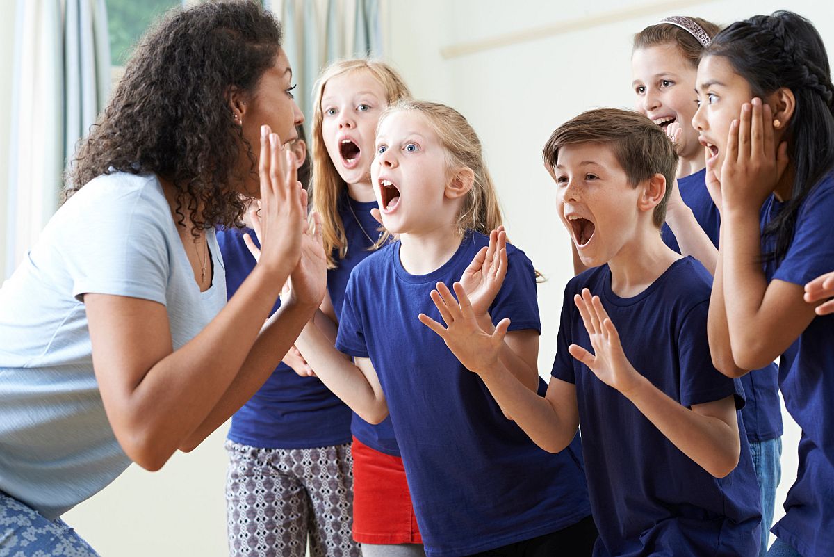 young children playing a clapping game with their teacher; concept: safe return of arts programs