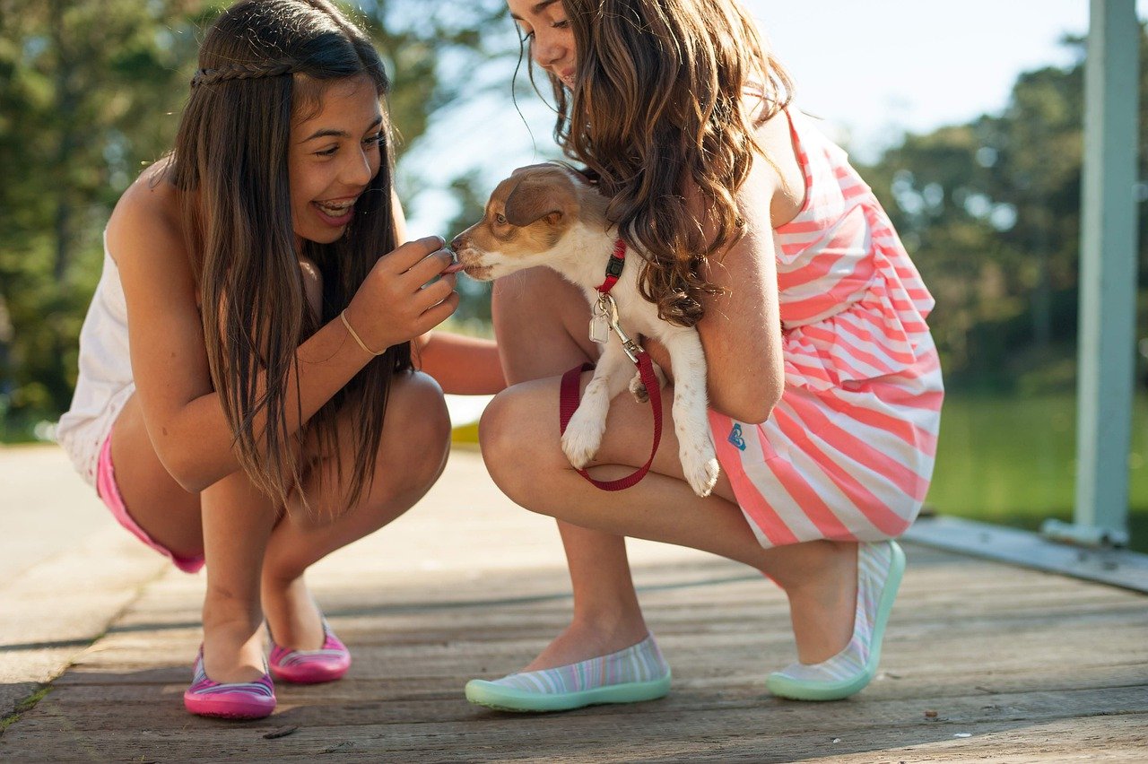 two children smiling, one holds a puppy; returning students concept