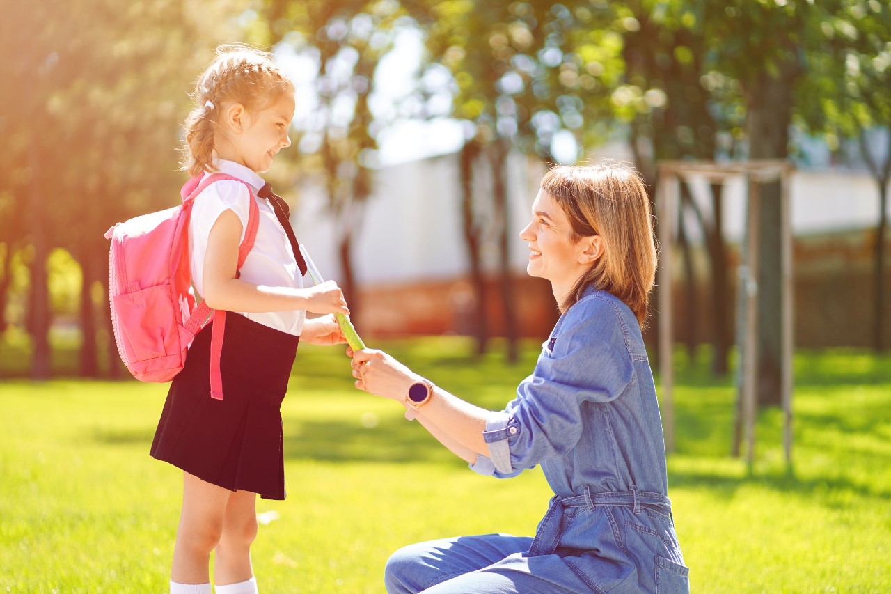 smiling mother sends her child off to school; classroom behavior concepts