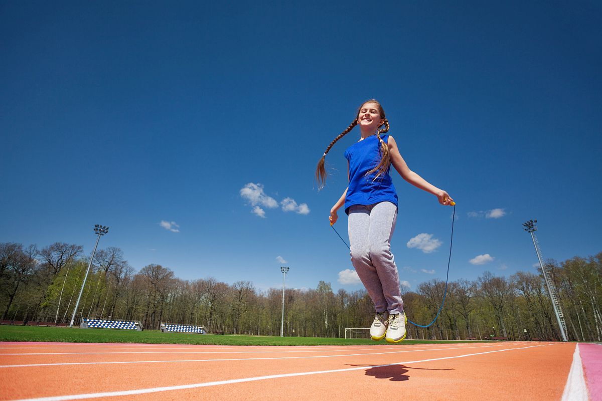 student skips rope on a track; return to gym class concept