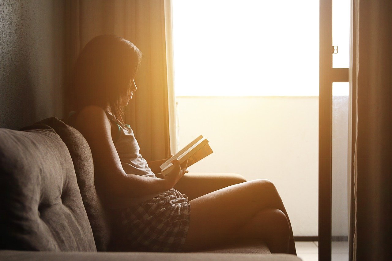 girl reading alone on a windowsill; concept: inclusive learning environment for neurodiverse students