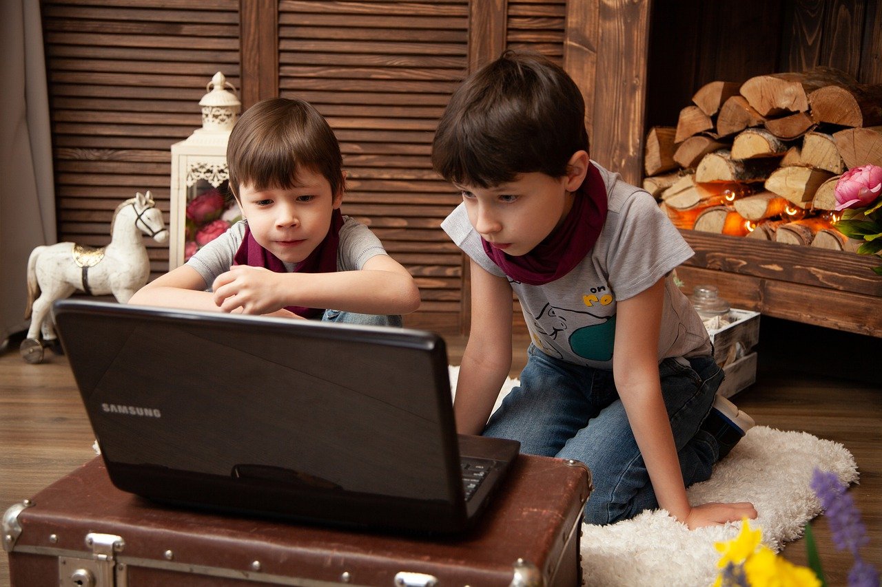 two young children use a laptop at home; concept: inclusive learning environment for neurodiverse students