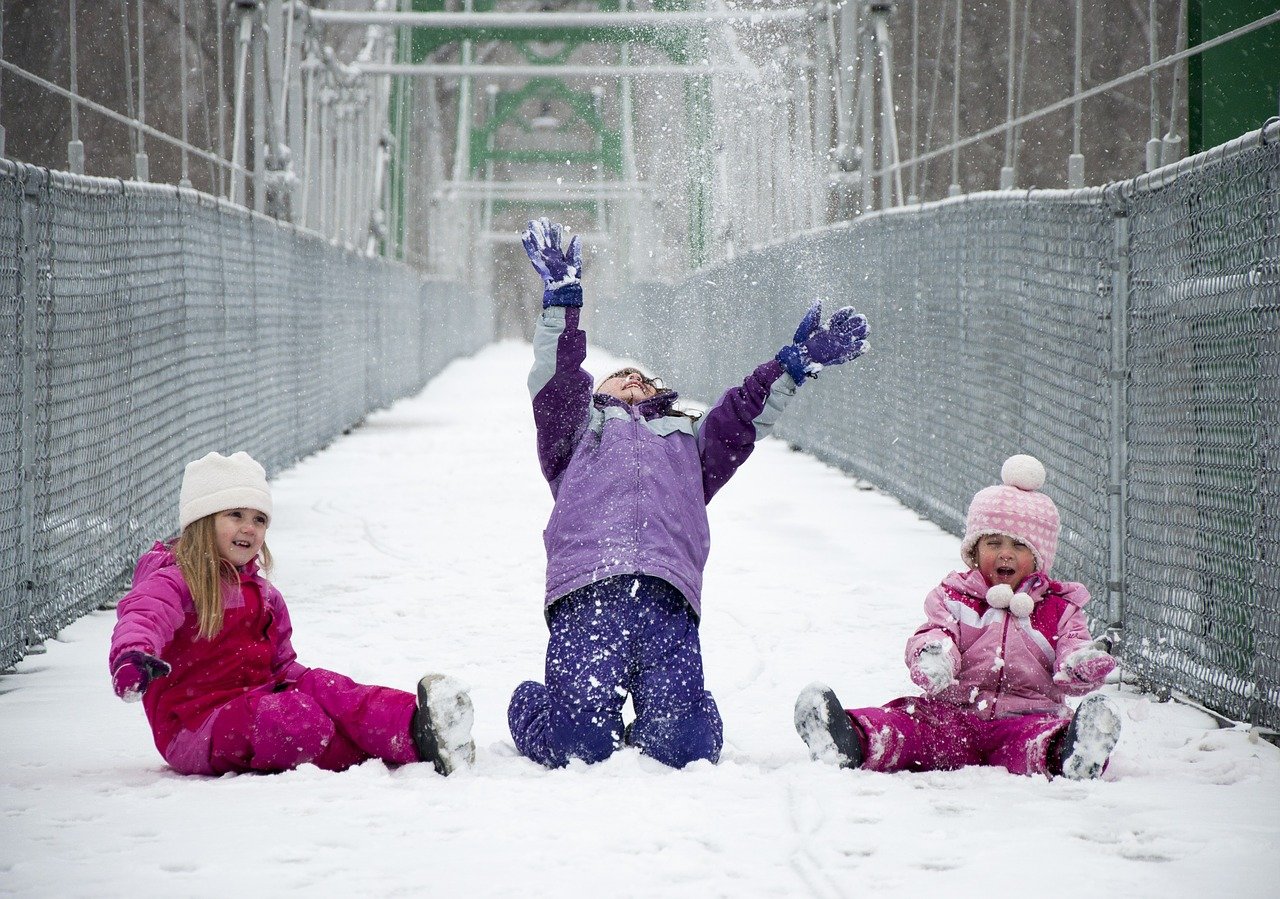 three kids play in the snow; remote learning and in-person learning concept