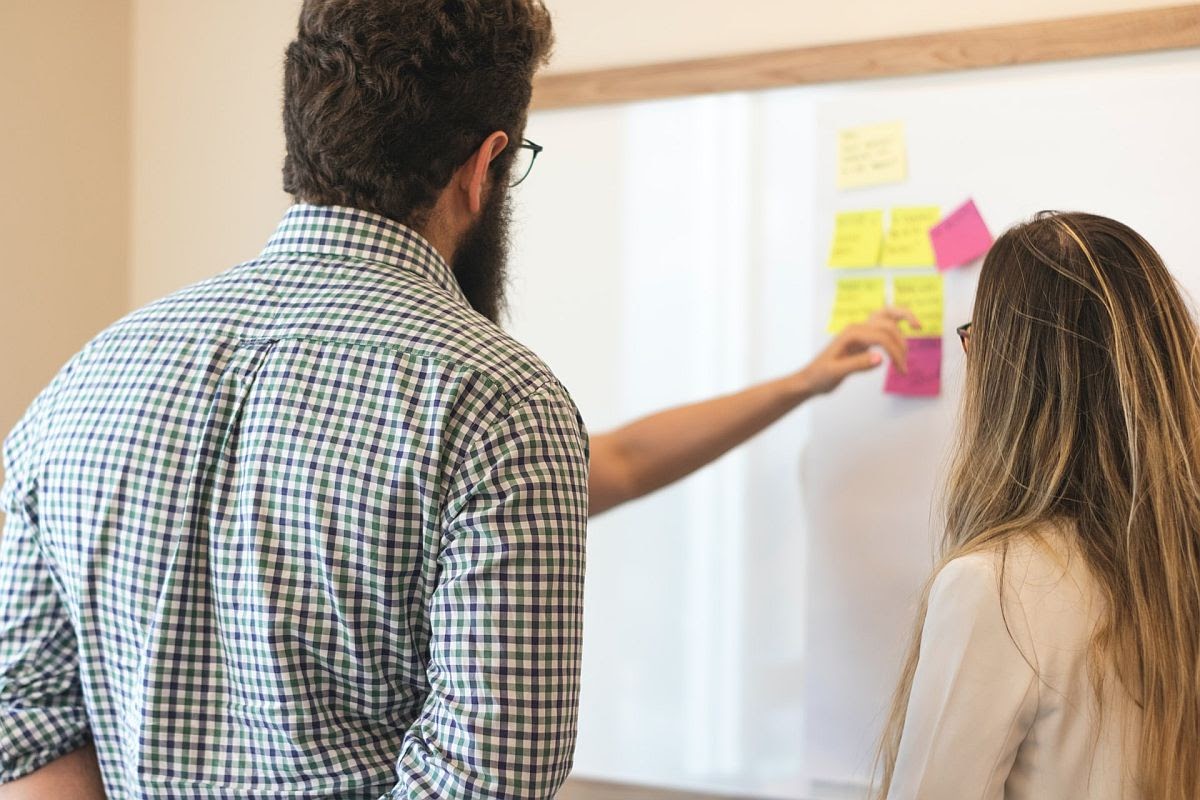 two teachers discuss while looking at a whiteboard; online tools concept