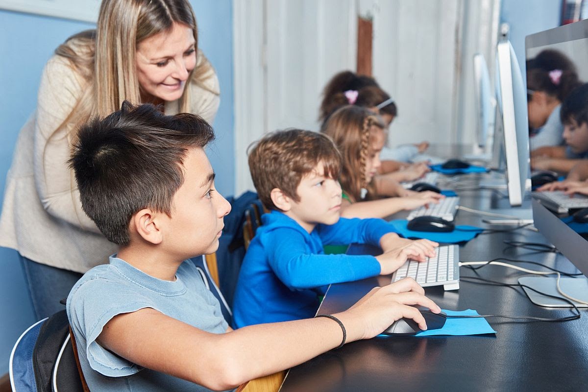 Group student and teacher at e-learning at primary school computer; incorporate screen-based learning with in-person learning concept