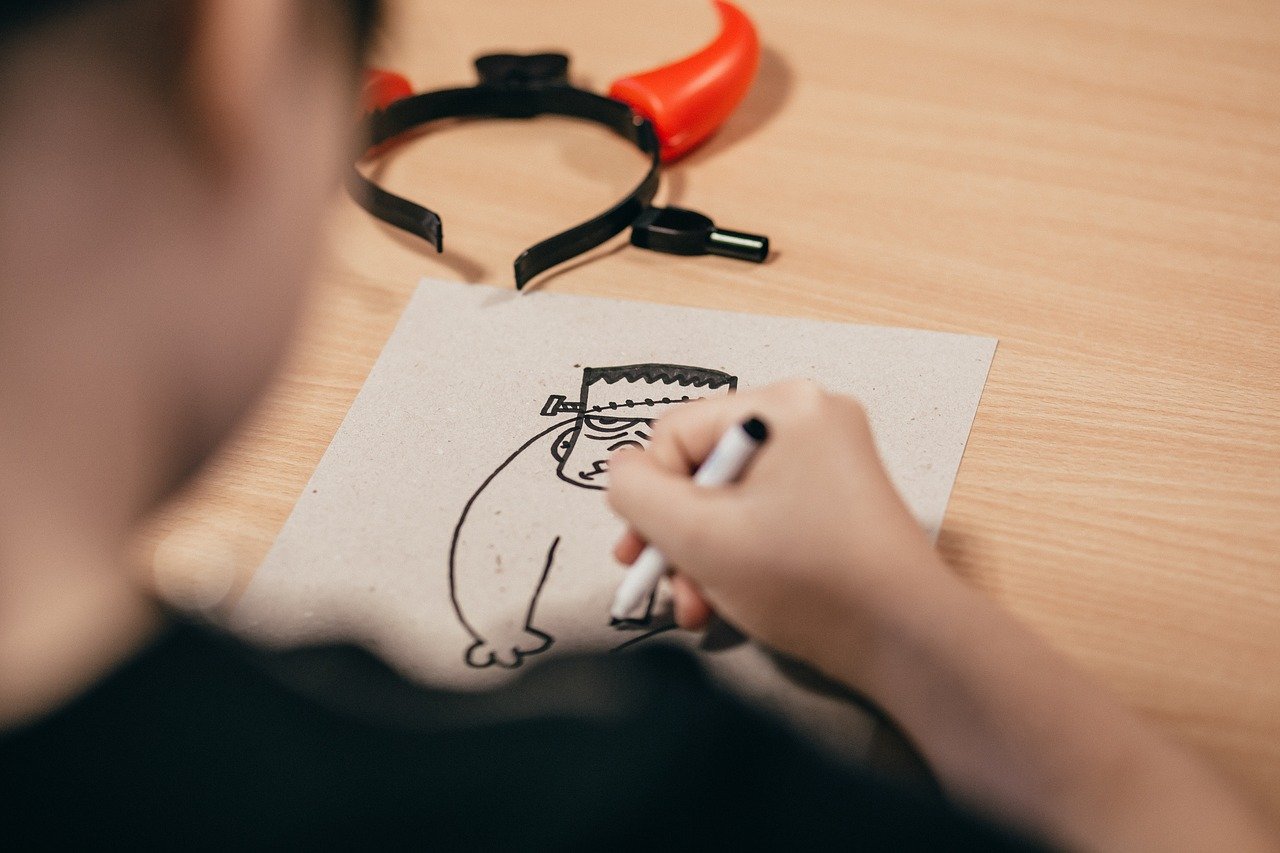 student using a marker to draw Frankenstein; halloween classic literature concept