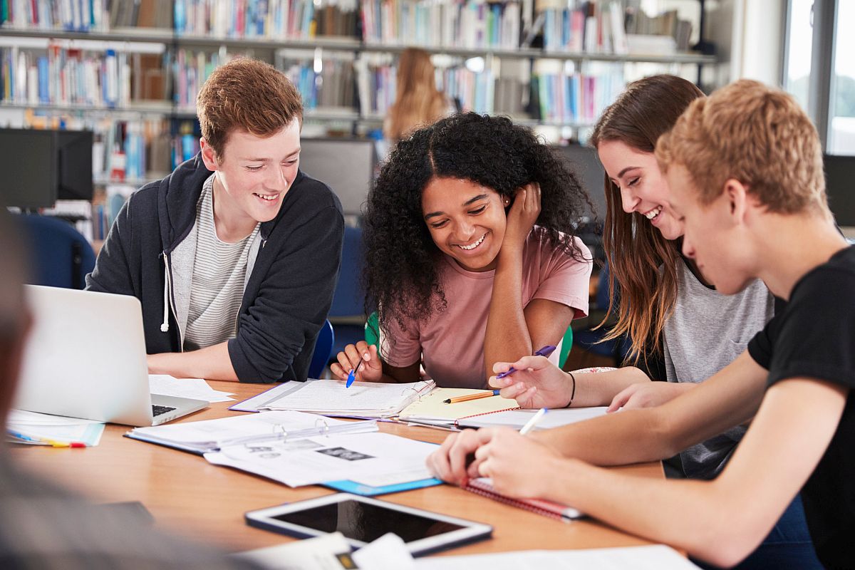 College Students Collaborating On Project In Library; group work and social-emotional learning concept