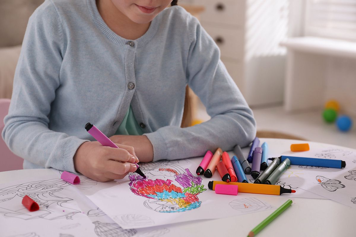 Child coloring drawing at table in room; self-calming strategies for students concept