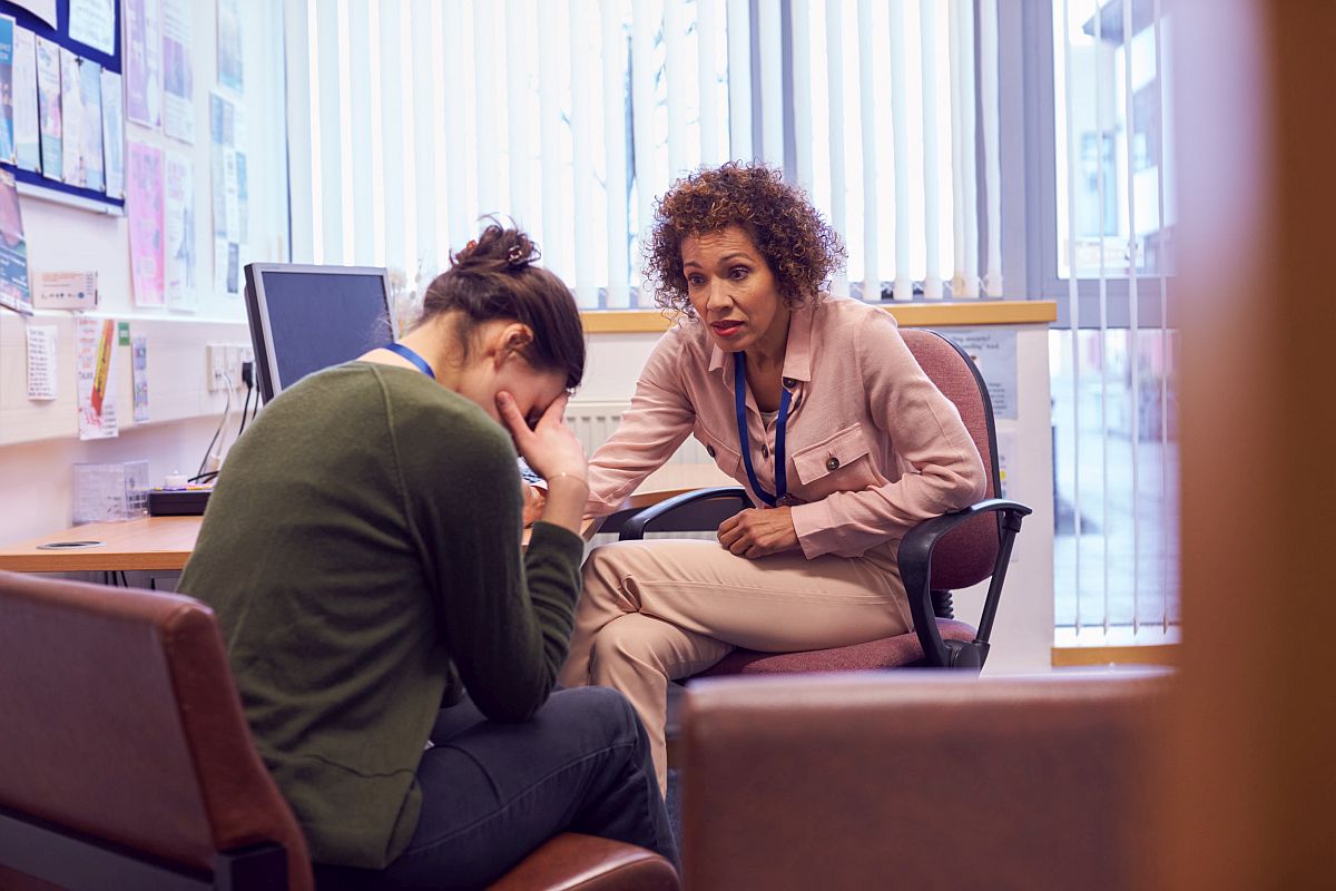 Female college student meeting with campus counselor; mental health of teachers concept