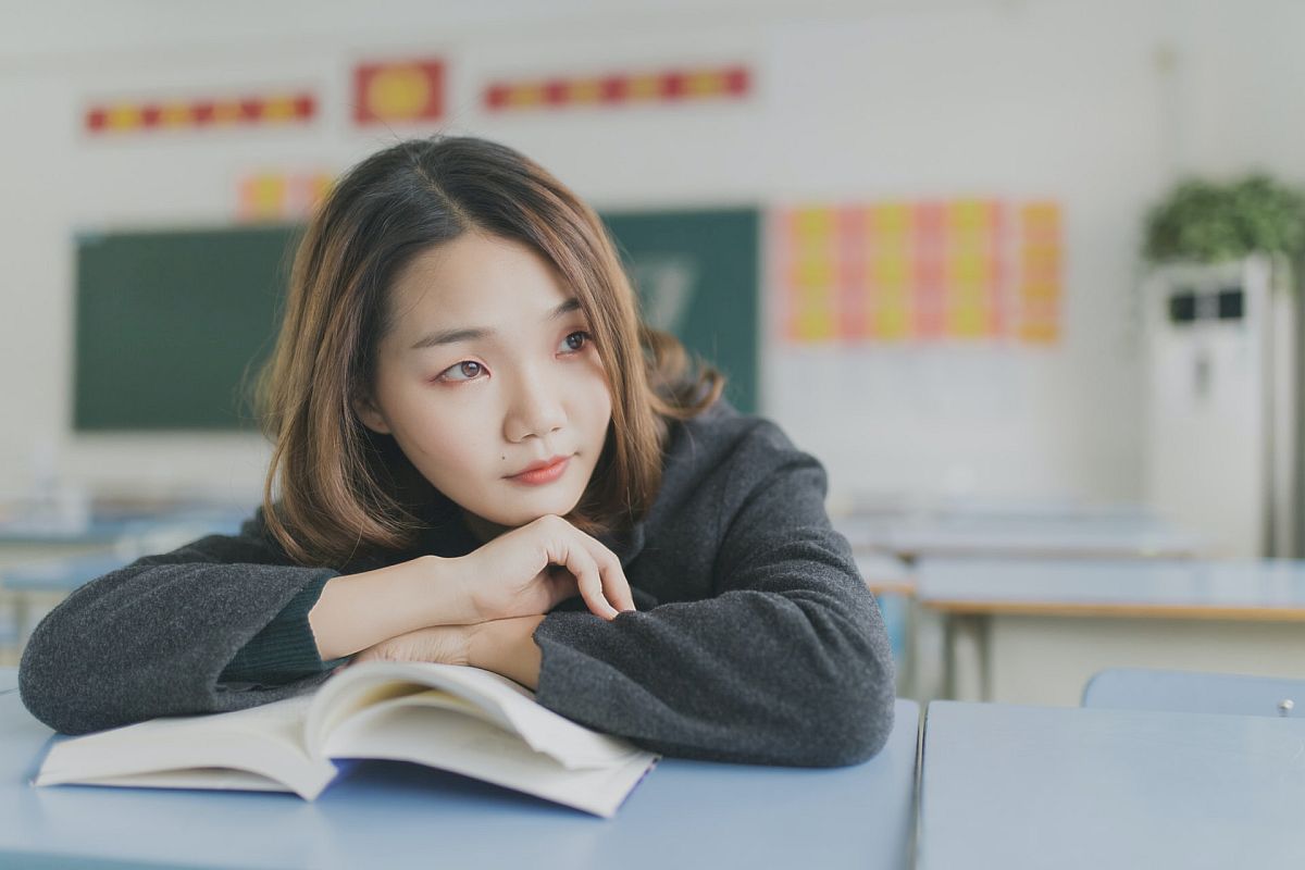 Student at desk in classroom with open book; English Language Learners concept