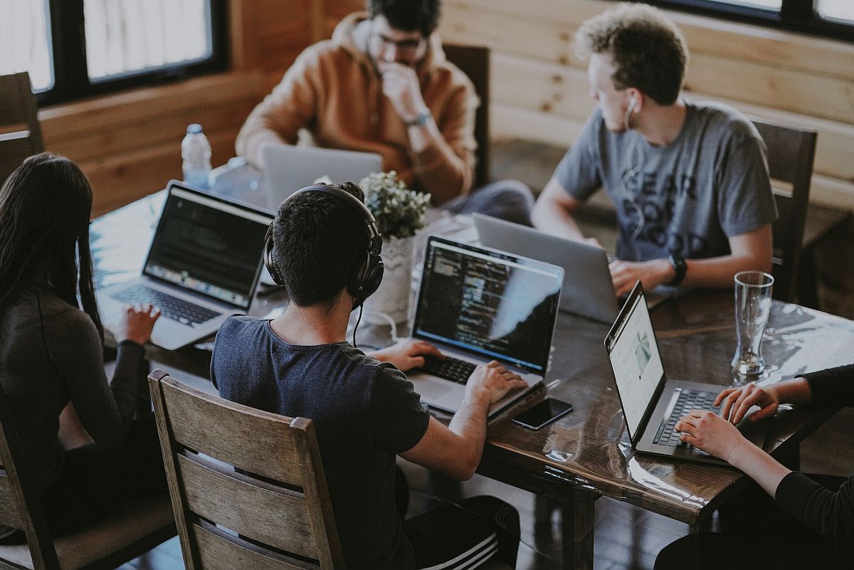 Young people sitting at a table, using laptops; edtech tools concept