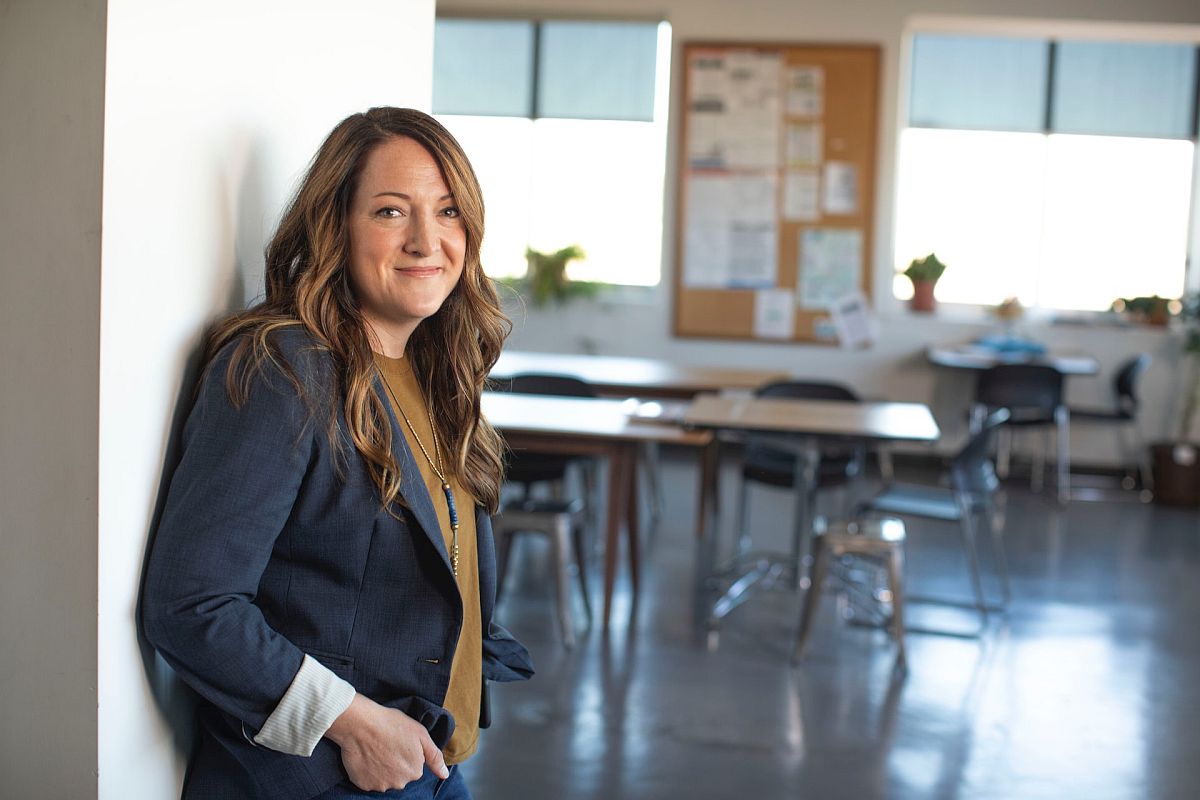 Woman smiling in empty classroom; paraprofessionals in education concept.