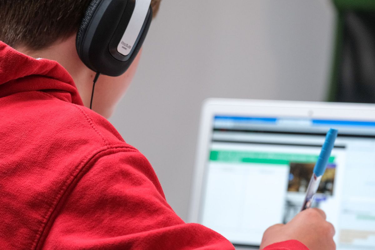 student wearing headphones work on laptop; technology grants concept