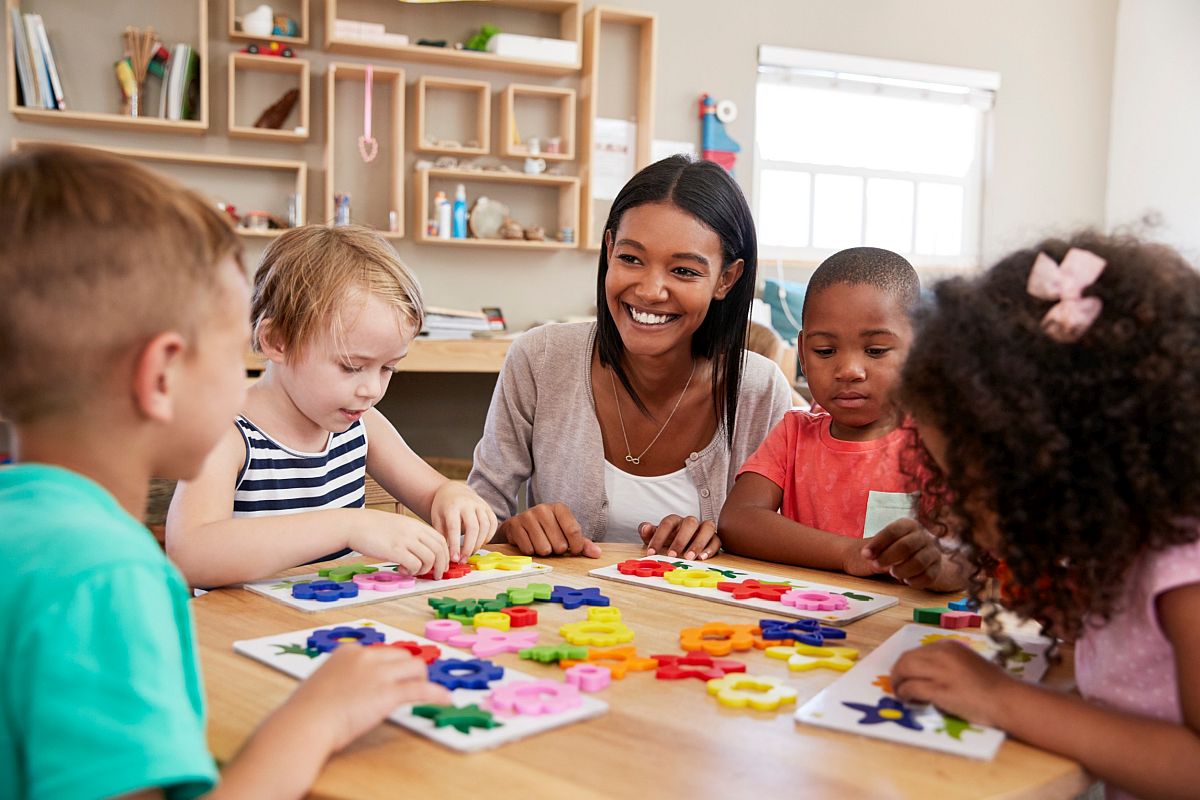 Teacher sitting at table with young students; help students with learning disabilities concept