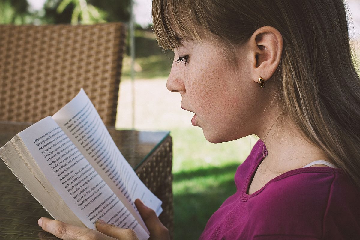 Young girl reading a book; reading specialists concept