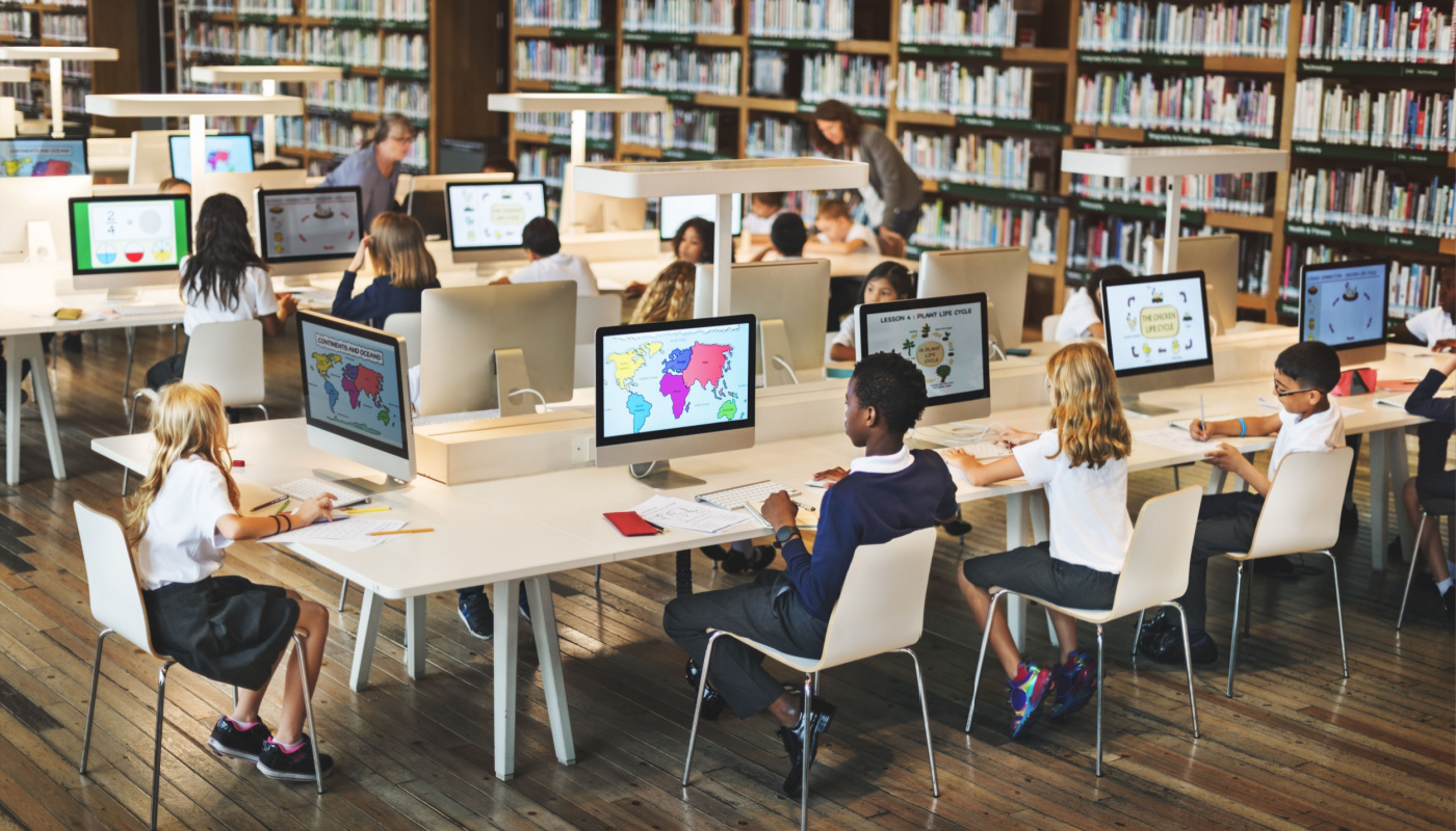 Students working on desktop computers in school library; school librarians concept