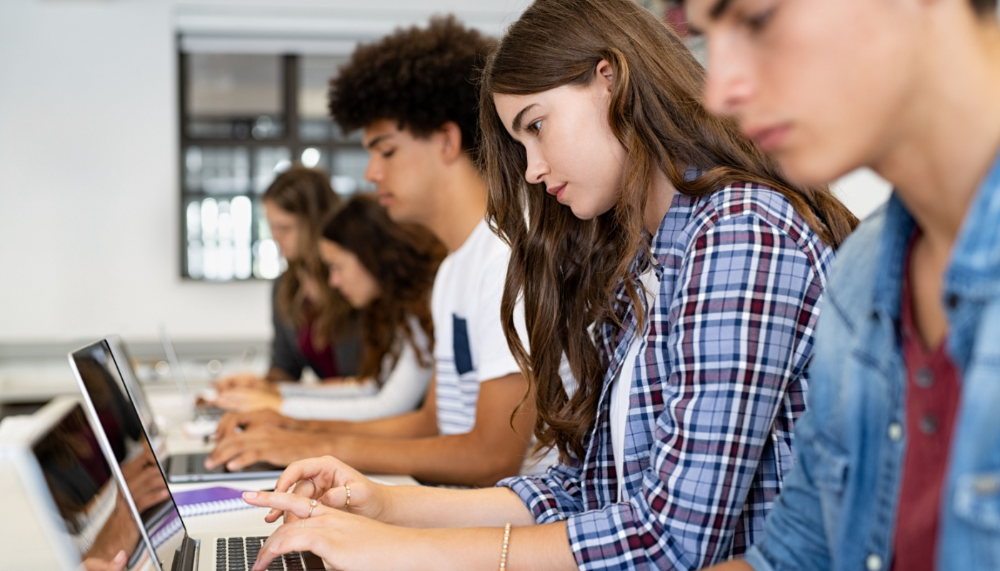 Older students working on laptops in a classroom; AI-generated content concept