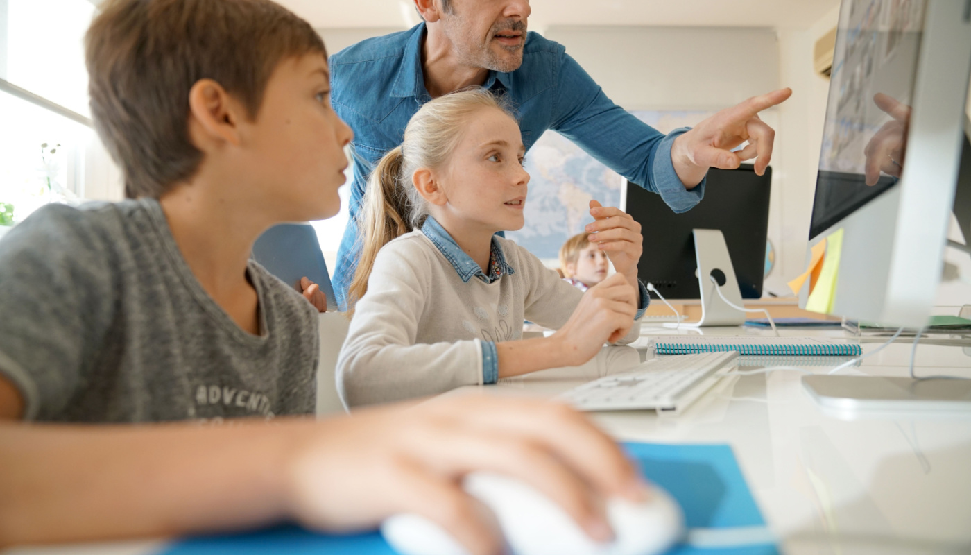 Teacher pointing to computer monitor, helping students; AI-generated content concept